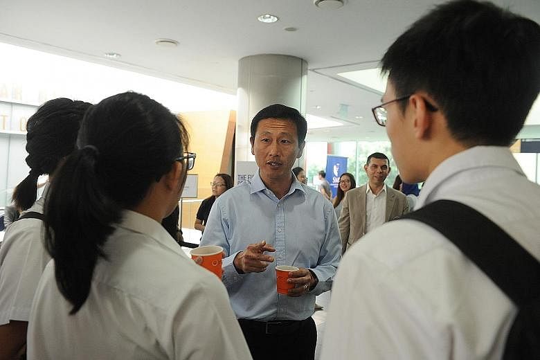 Mr Ong Ye Kung interacting with students before The Straits Times Education Forum 2016, with ST editor Warren Fernandez behind him.