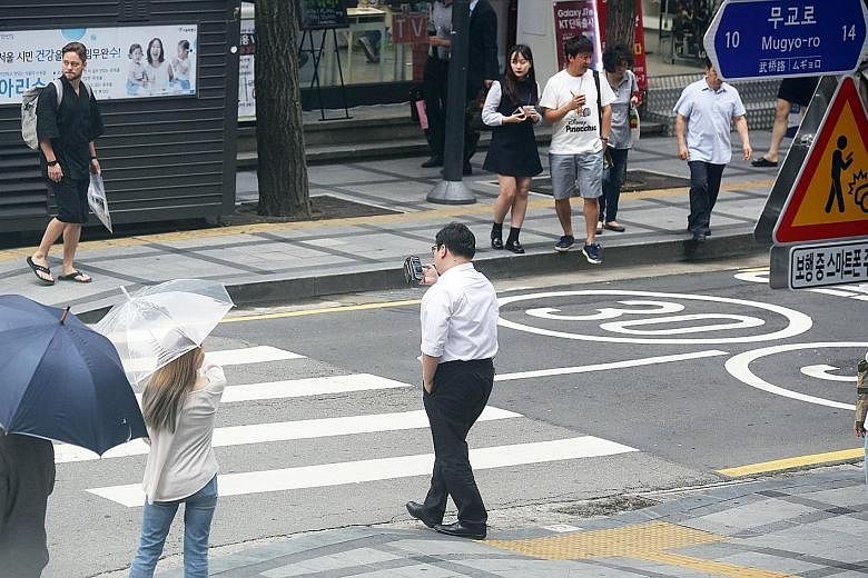"Smartphone zombies" spotted at a main pedestrian crossing near Seoul's City Hall last week, oblivious to the warning signs.