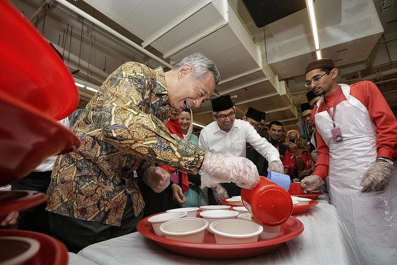 PM Lee and Dr Yaacob pouring out porridge for the iftar at Al-Islah Mosque yesterday. About 350 community and religious leaders, mosque volunteers, and foreign workers who work nearby gathered to break fast with them.