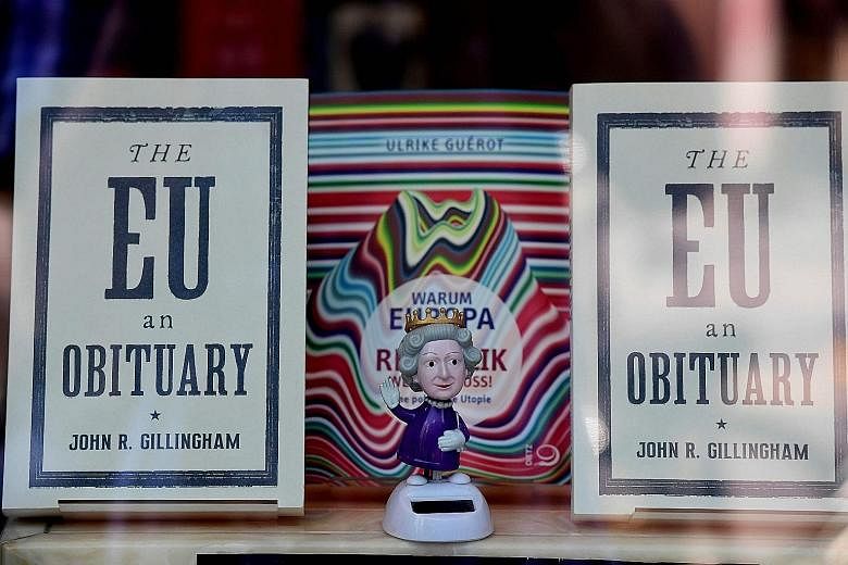 A figurine depicting Britain's Queen Elizabeth standing between copies of the book The EU An Obituary by John R. Gillingham, in a bookshop window in Berlin.