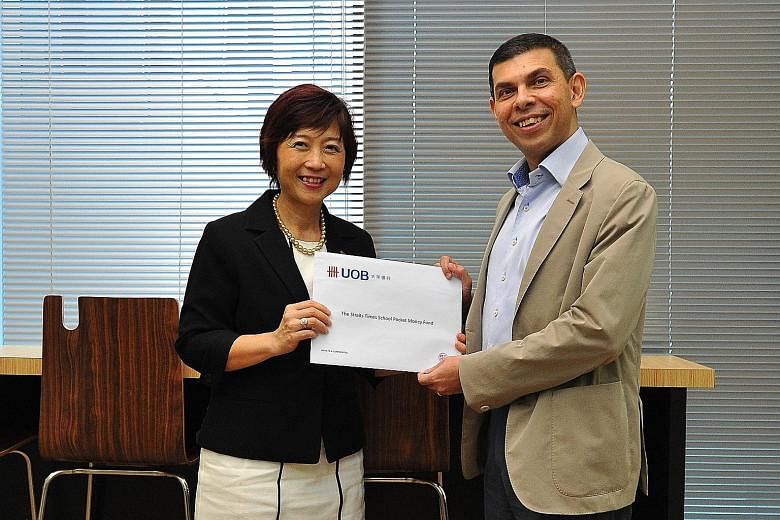 UOB's Ms Rosalind Lee presenting a cheque for the donation to ST editor Warren Fernandez yesterday.