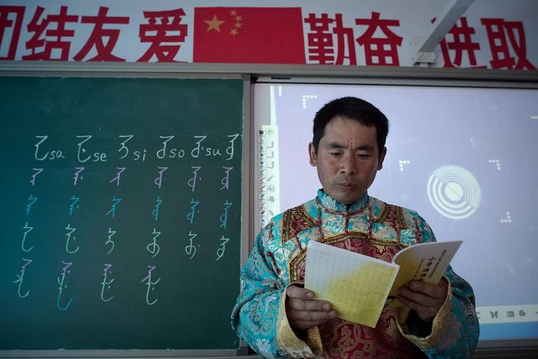 Mr Shi Junguang, a teacher in a village primary school in Sanjiazi, in the north-eastern Heilongjiang province, dressed in a red and turquoise robe with gold sleeves, which is reminiscent of the Manchus' traditional apparel. On the blackboard next to him 