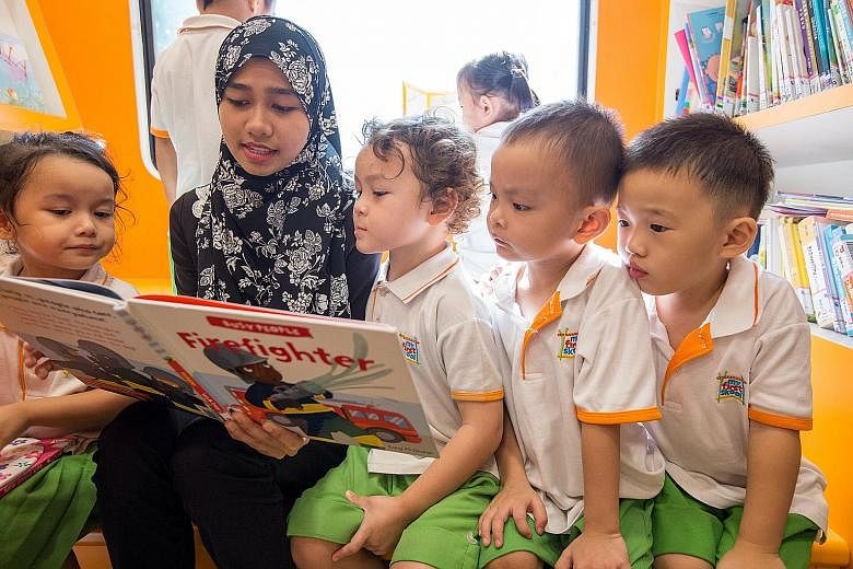 (Clockwise from right) Children enjoying a book on the NLB's "mini-Molly", one of two mini mobile libraries that will be open to the public at Bishan-Ang Mo Kio Park and East Coast Park on Saturday.