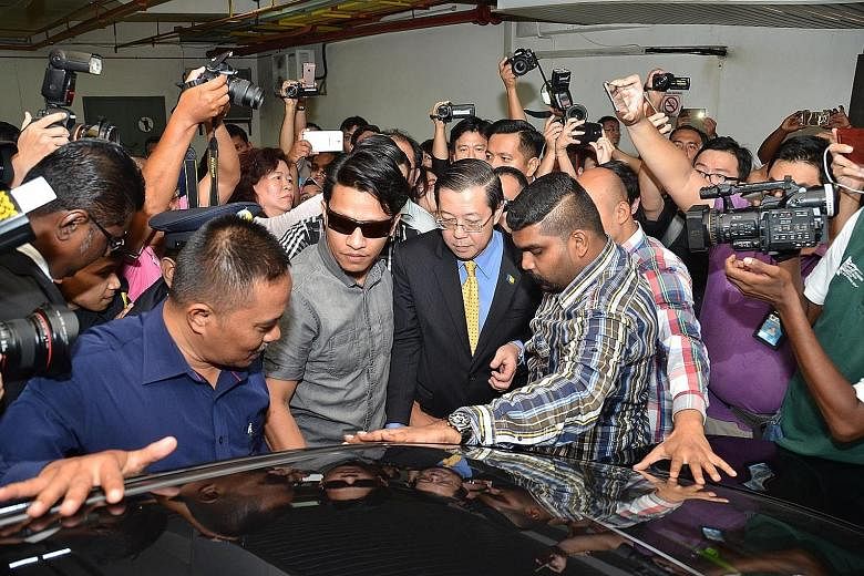 Penang Chief Minister Lim Guan Eng being led away by Malaysian Anti-Corruption Commission officials and plainclothes policemen yesterday. The DAP leader, who denies the graft accusations, was taken to the MACC office in Penang for an arrest warrant t