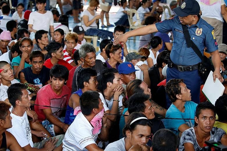 A policeman talking to residents, who admitted to being drug users, at a police camp, after more than 700 people gave themselves up to policemen and local government officials in Quezon city, the Philippines, last Friday.