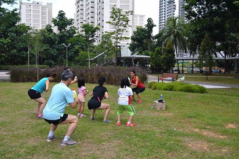 Led by Miss Shereen Ng, Clementi residents do squats using household items such as detergent bottles at Firefly Park in Clementi.