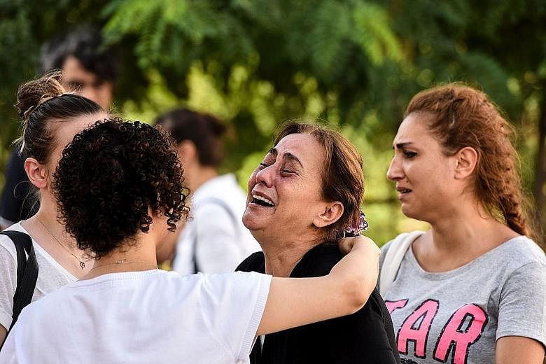 Right: A mother of one of the victims grieving outside a forensic medicine building close to Istanbul's airport yesterday. The attack left at least 41 people dead and 239 others injured. Above: Forensic experts at work outside Istanbul's Ataturk airp