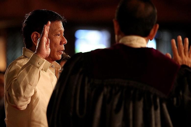 Mr Duterte, in a barong, taking his oath of office as the Philippine President at Malacanang Palace yesterday. The tough-talking, gun-toting former mayor of Davao City won the presidential election in May. Crowds gathering outside the Malacanang Pala