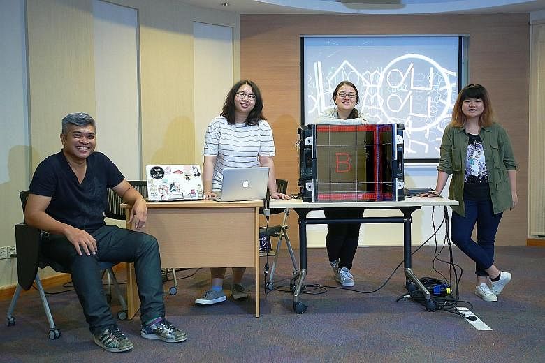 (From far left) Mentor Zullikhan Abdullah and interactive media programme participants Hazel Sim, Carissa Chew and Tok Jin Yu with a mock-up of the 360-degree enclosed cube installation that will be shown in front of Ngee Ann City Civic Plaza.