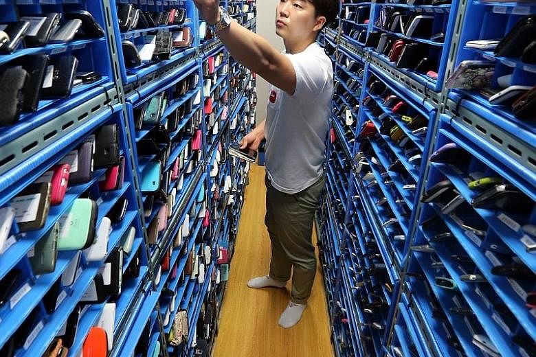 A worker putting away lost smartphones at the Mobile Phone Lost and Found Centre in Seoul on Thursday. Run by the Korea Association for ICT Promotion and the nation's three mobile networks, the facility keeps the devices for nine months, says the wor