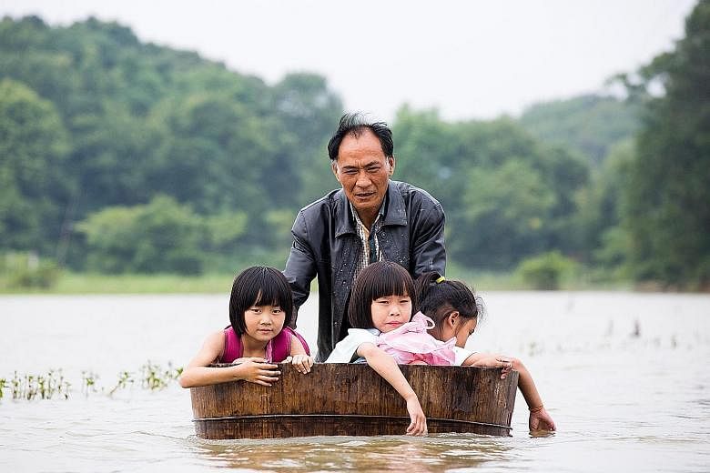 A man pushing a tub carrying children as he gets them back home after school due to massive flooding in Duchang, Jiangxi province, China, on Monday. Heavy rains in the region disrupted train services, made highways impassable, and forced thousands of