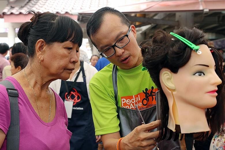 Mr Lim explains some basic hair trimming techniques to Madam Ong Mok Lian, 64. He had picked up his skills at a barbering course offered as part of the People's Association DIY Series.