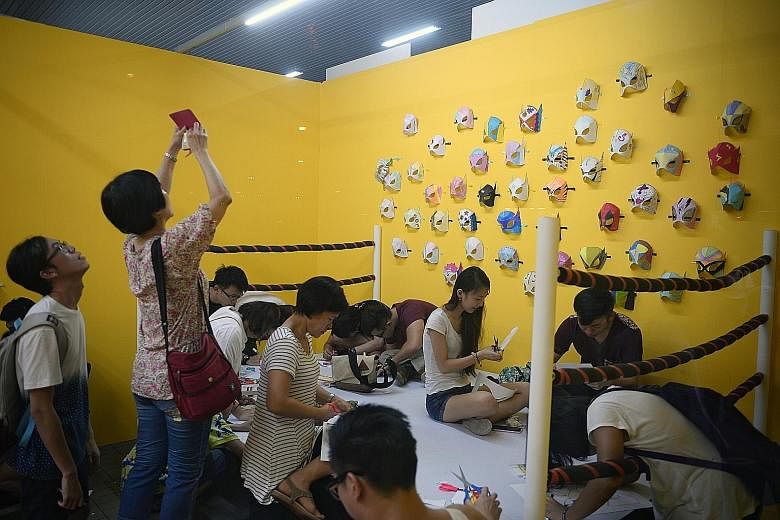 Visitors make paper masks as part of the Coming Hom3 art exhibition, held at Kovan Hub. The exhibition consists of a life-size, six-room "art home", complete with a toilet, which screens a video of Singaporeans talking about their stresses, and a kit