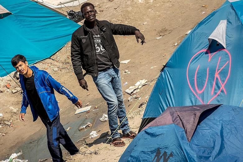 Migrants in the "Jungle" camp in Calais, France, with a tent tagged "UK" in a heart-shaped logo. The Leave campaign emphasised the high levels of migration as a key factor in the Brexit referendum. Outgoing Prime Minister David Cameron says immigrati