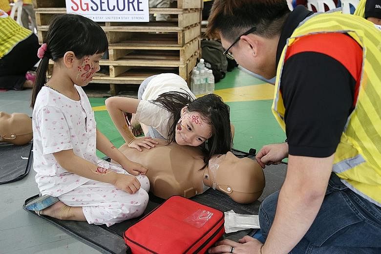 Sisters (from left) Quek Gek Ling, six, and Quek Gek Boon, eight, learning about CPR from a member of the Community Emergency Response Team, Mr Adris Chong, 31, at the Our Blocks Rock event in Hougang yesterday.