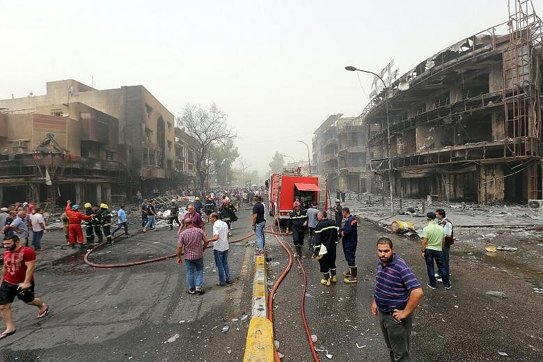 Shocked Iraqis at the site of the suicide car bombing in Baghdad's central Karrada district yesterday. At least 125 people were killed and 200 others were wounded in the suicide attack.