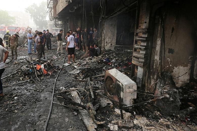 Iraqis inspecting the damage at the site of a suicide car-bomb explosion yesterday in Baghdad's central Karrada district. The blast, which ripped through an area where many people go to shop ahead of the holiday marking the end of the Muslim fasting 