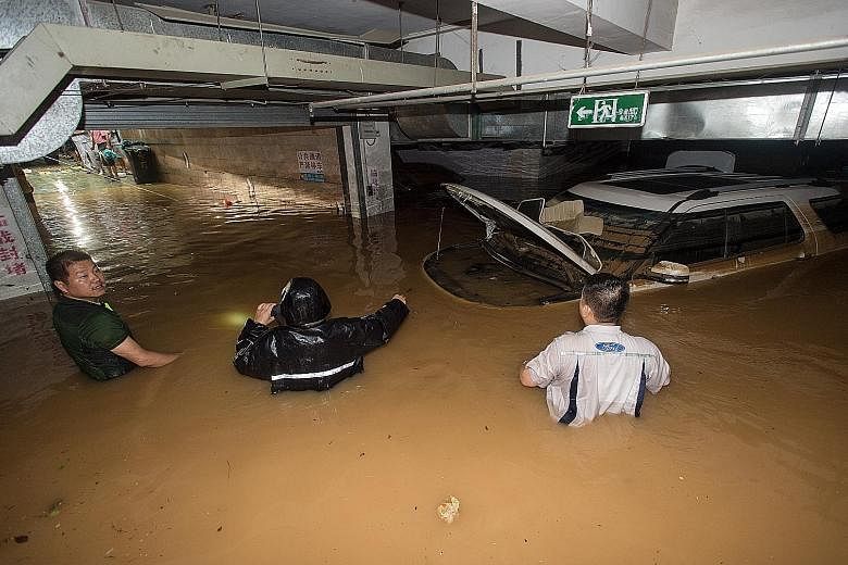 People trying to remove a car from a flooded parking garage in Wuhan, in China's central Hubei province, on Saturday. In southern China, heavy rain has left 14 people dead and eight others missing since Thursday.