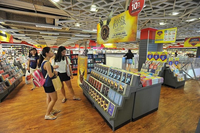 Promotional materials and merchandise on Harry Potter on display (above) at Popular's Bras Basah Complex outlet; and a staff member donning a wizard hat.