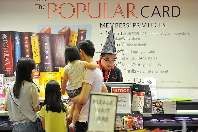 Promotional materials and merchandise on Harry Potter on display at Popular's Bras Basah Complex outlet; and a staff member donning a wizard hat (above).