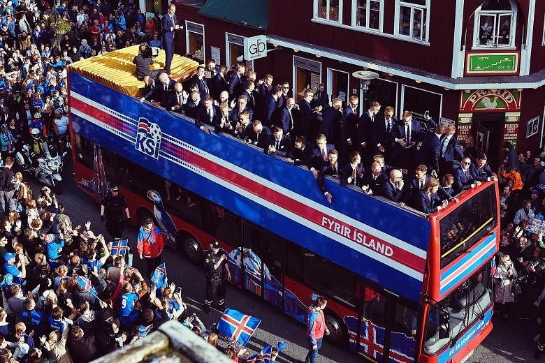 Members of the Iceland team are feted by fans as they are taken through the streets of Reykjavik, the national capital, on an open-top bus on Monday on their return from Euro 2016. The smallest nation at the tournament had stunned fans and pundits by