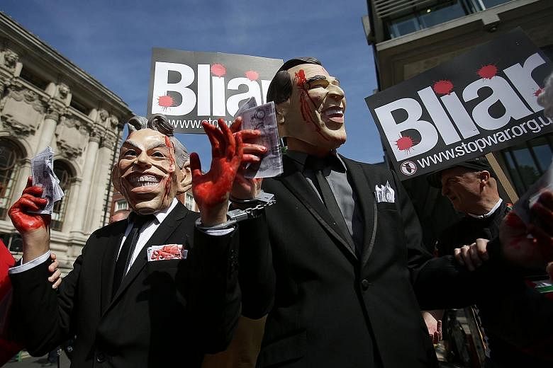 Demonstrators wearing masks depicting former British Prime Minister Tony Blair (left) and former US President George W. Bush protesting in London yesterday as they awaited the outcome of the Iraq War Inquiry. Sir John Chilcot, who led the seven-year 