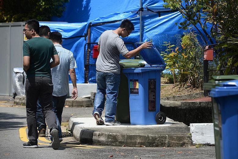 Members of the Singapore Police Force looking for clues in Taman Warna private estate in Holland Village (above) yesterday. They were seen packing up their equipment outside the bank branch (below). The suspect is still at large.