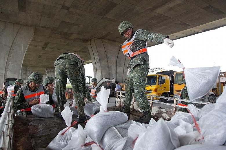 Soldiers distributing sand bags to residents in Ilan county in north-east Taiwan yesterday. More than 35,000 soldiers are on standby to help with evacuations and disaster relief.