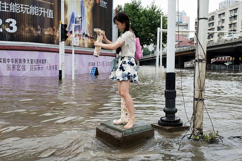 A woman emptying water out of her boot in Wuhan, which received in a week almost as much rain as London gets in a year.