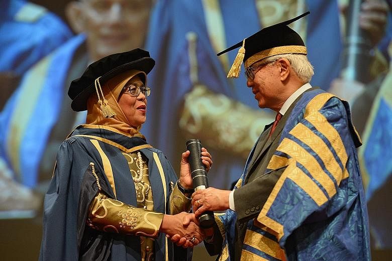 Madam Halimah receiving her scroll from President Tan, who is also NUS chancellor, during a ceremony at NUS yesterday. The accolade puts her among luminaries such as founding Prime Minister Lee Kuan Yew.