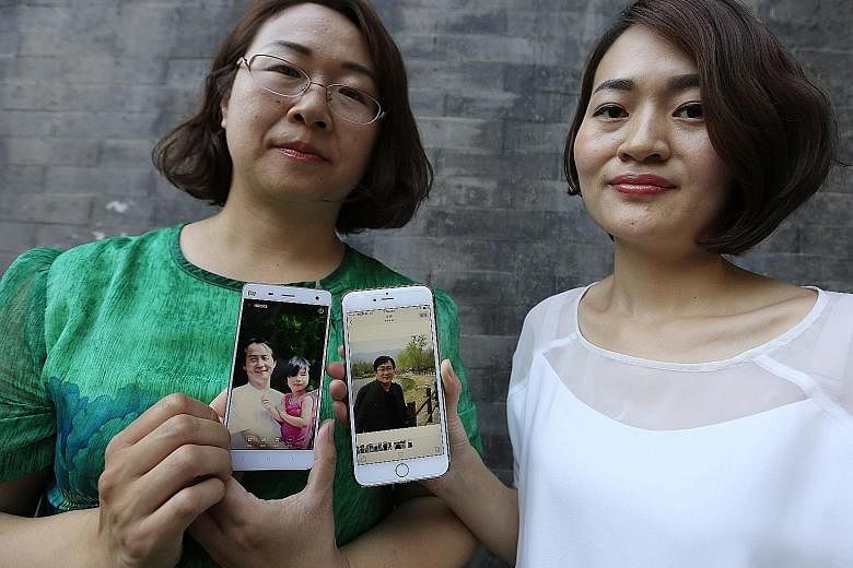 Ms Wang Qiaoling (left) and Ms Li Wenzu with their mobile phones showing photos of their husbands, human rights lawyers Wang Quangzhang and Li Heping, who were arrested last year.