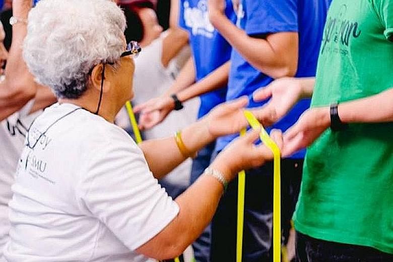 SMU students of Project Inspirar guiding the elderly through the steps of a resistance band exercise at an event held at the Toa Payoh East Community Club. SMU's 2015 graduating class contributed 80 per cent more than the 80 hours of community work t