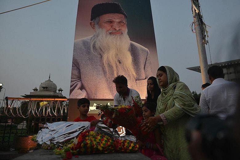 Pakistanis placing flowers before a portrait of Mr Edhi in the capital Islamabad on Saturday. Mr Edhi was revered for setting up maternity wards, morgues, orphanages, shelters and homes for the elderly.
