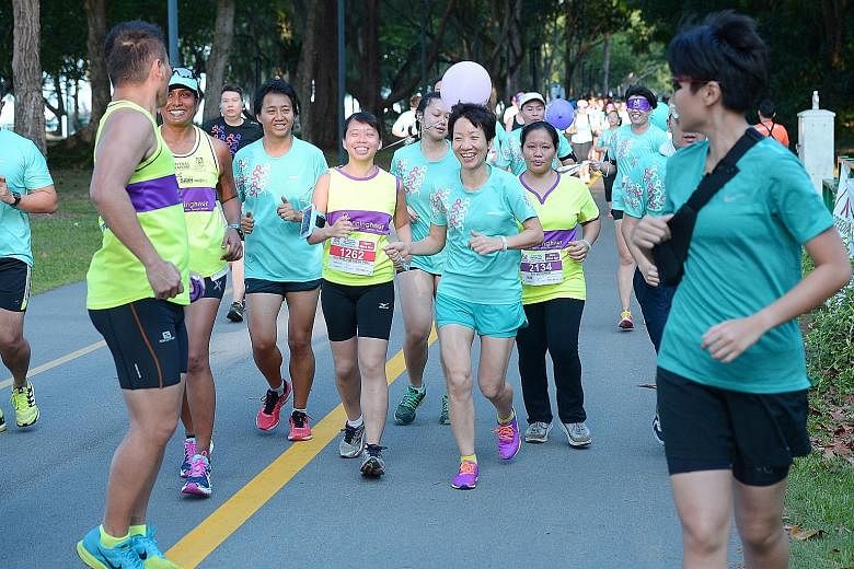Ms Poo (wearing number 1262), being guided with a hand-held tether by Ms Fu in the Runninghour 2016 race yesterday. Just before this, the Minister for Culture, Community and Youth had run blindfolded for 500m.