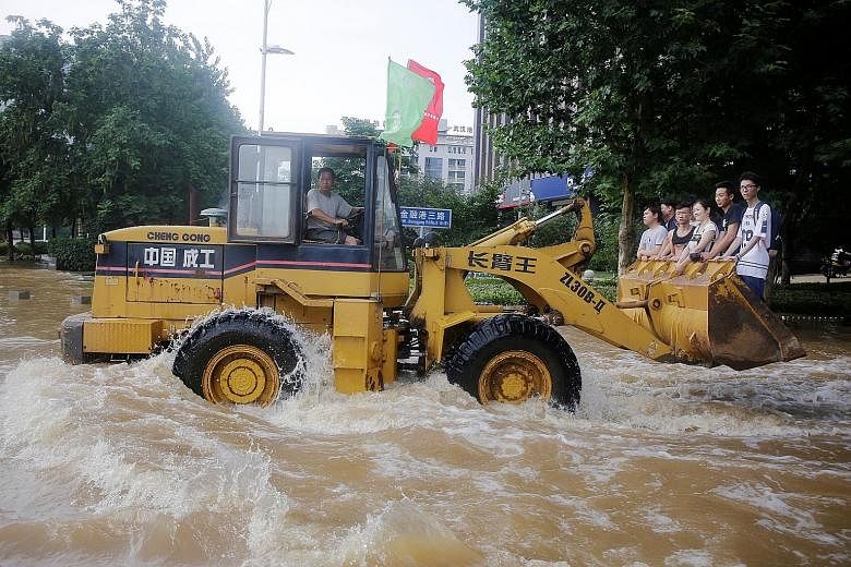 Residents of Wuhan in Hubei province heading to work on an excavator last Friday through churning floodwaters. China has been experiencing widespread flooding as torrential rains batter wide swathes of the country.
