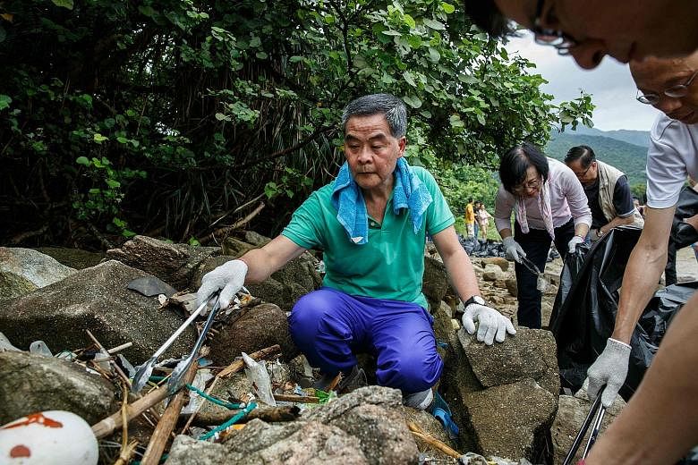Mr Leung helping to pick up refuse washed ashore at the top of a beach in Hong Kong yesterday. He blamed the mainland for the rising amount of rubbish on the city's beaches.