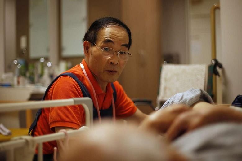 Mr Suzuki, 72, helping a resident at a nursing home in Tokyo. Mr Suzuki is atypical in Japan, where the corporate structure is stacked against widespread employment of older workers. At many companies, the career ladder for employees ends at age 60 or ear
