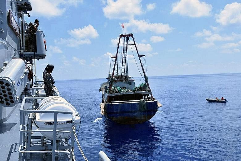 Indonesian navy officers aboard KRI Imam Bonjol (far left) inspecting a Chinese-flagged fishing boat near the Natuna Islands.