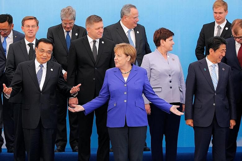 German Chancellor Angela Merkel (in blue) gesturing between Chinese Premier Li Keqiang (left) and Japanese Prime Minister Shinzo Abe as they posed with other heads of delegations for a group photo during the Asia-Europe Meeting in Ulaanbaatar, Mongol