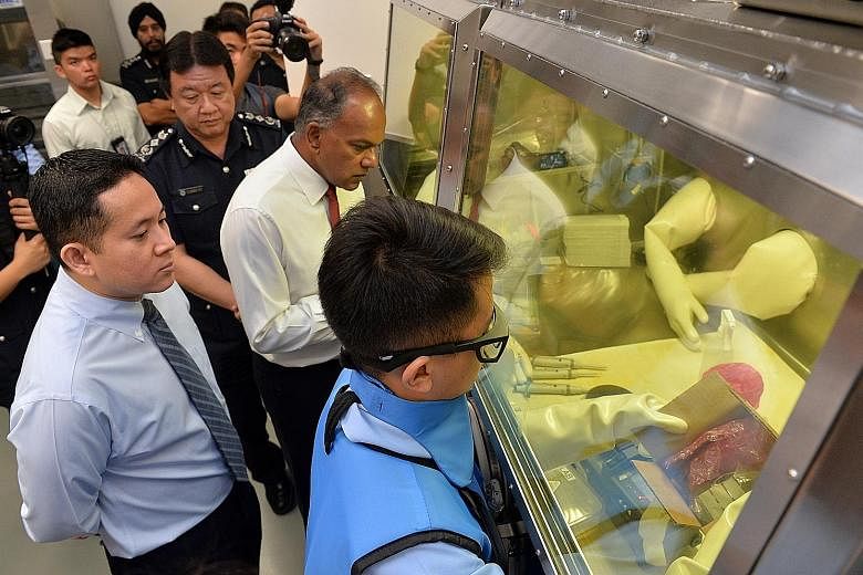 Mr Shanmugam touring the Radioactive and Nuclear Analysis Laboratory yesterday with (from left) Parliamentary Secretary Amrin Amin and ICA Commissioner Clarence Yeo. The lab is part of the Protective, Analytical and Assessment Facility in Pasir Panja