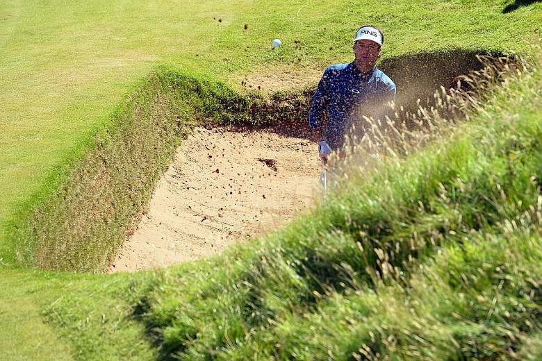 US golfer Bubba Watson blasting out of the Coffin Bunker at the side of the eighth hole at Royal Troon, on his way to a triple-bogey six. The Postage Stamp is one of the most unforgiving par threes.