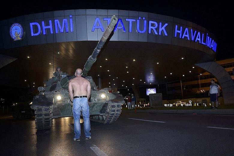 A defiant man standing in front of an army tank at Ataturk airport in Istanbul yesterday as the country came to grips with an attempted coup the day before. People running away on the Bosphorus Bridge during clashes in Istanbul yesterday. There were 