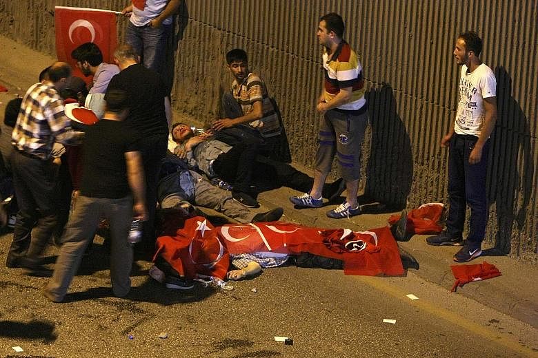 Injured victims being tended to on a street in Ankara yesterday, while a body was draped in the Turkish flag. A confrontation in Taksim Square, Istanbul, yesterday. Less than 12 hours after the coup was attempted on Friday by elements of the military