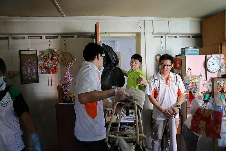 Volunteers moving furniture and trash out of an elderly resident's room to facilitate cleaning. They were part of this year's Project GroomOver, an annual charity drive organised by SGH.