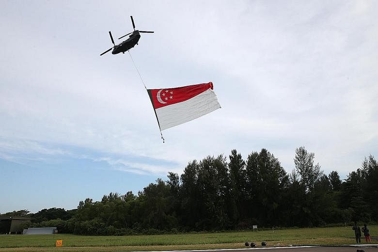 Left: The team loads the flag into the helicopter for its move from Pulau Sudong to Sembawang Air Base. Above: The flag will fly past the National Stadium before going across the southern coast.