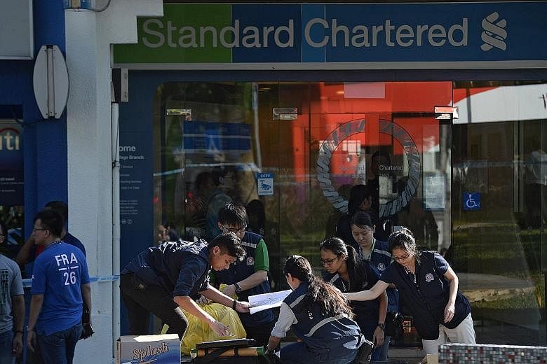 Police and Criminal Investigation Department officers at the Standard Chartered Bank in Holland Village after a robbery there last Thursday. Before investigators could figure out Roach's identity, he had fled Singapore the same day for his next stop 