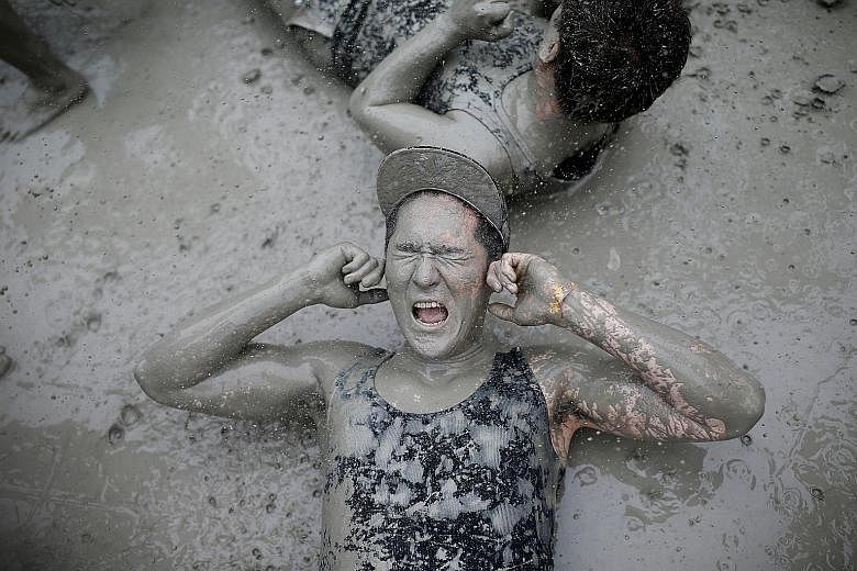 Tourists rolling around in the mud during the Boryeong Mud Festival at Daecheon beach in Boryeong, South Korea, yesterday. The annual festival, which runs from July 15 to 24, aims to encourage the use of mud for cosmetic skincare and promote tourism 