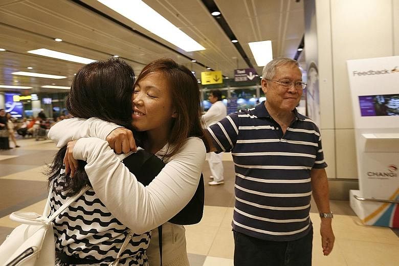 Ms Grace Feng, 33, hugging her mother, Madam Mary Lan, 66, at Changi Airport on her return from Turkey yesterday. Beside her is her father, Mr Philip Feng, 68. Several Singaporeans in Turkey resumed their journeys or arrived home last night. SEE TOP 