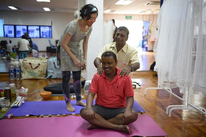 Welders Krishna Rai (in yellow), 50, and Athi Ramamoorthy, 32, learning the art of massage at a "roadside spa", guided by artist Ng Xi Jie, during the Kapor ChatParty held at Kampong Kapor on Sunday. 