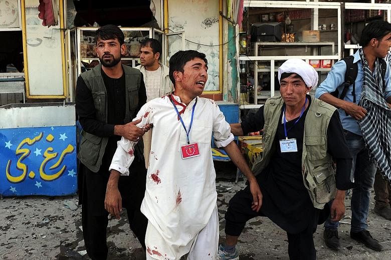 An injured victim being helped amid yesterday's carnage in Kabul. The bomb explosions, which targeted members of the Shi'ite Hazara community who had gathered for a protest, were claimed by ISIS. The deadly attack is a sign that ISIS is making steady